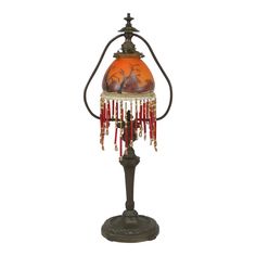 an old fashioned lamp with red beads hanging from it's stand on a white background