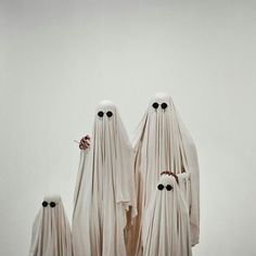 three ghostly people standing in front of a white wall