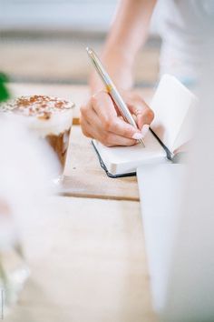 a person writing on a piece of paper with a pen