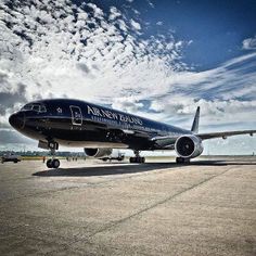 an airplane is parked on the tarmac under a cloudy sky