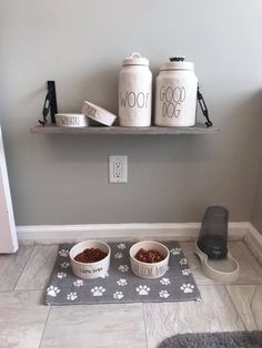 two bowls with food in them sitting on the floor next to a dog bowl and water dispenser