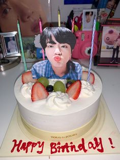 a birthday cake with a photo of a boy sticking out his tongue and strawberries on top