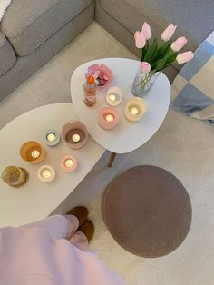 a table with candles and flowers on it next to a couch in a living room