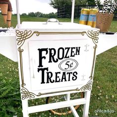 a sign that says frozen treats on it in front of some grass and trees with flowers