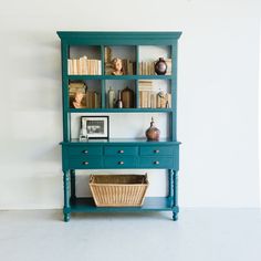 a blue bookcase with books and baskets on it