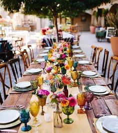 a long table with plates and vases on it is set for an outdoor dinner