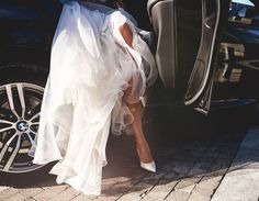 a woman in a white dress stepping out of a car with her feet on the door