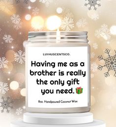 a candle with a quote on it sitting in front of snowflakes and lights