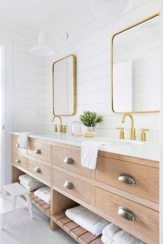 a bathroom with two sinks and gold mirrors