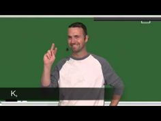 a man standing in front of a blackboard giving the peace sign