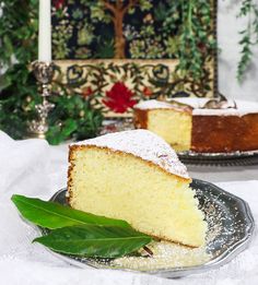 a slice of cake on a plate next to another piece of cake with powdered sugar