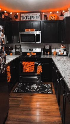 a kitchen decorated for halloween with black cabinets and orange accents