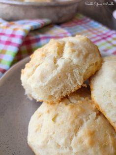 three biscuits stacked on top of each other on a plate next to a bowl of food