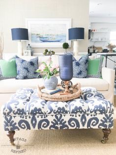 a living room with blue and white decor on the couch, coffee table and ottoman