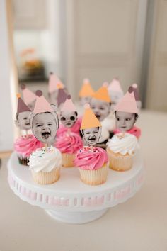 some cupcakes with faces on them are sitting on a cake plate in front of a mirror