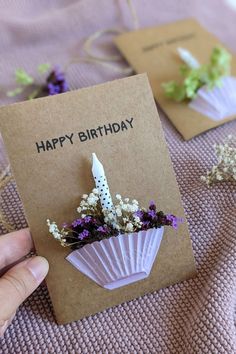 a person holding a birthday card with flowers in it