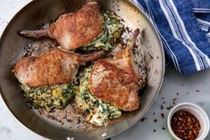 three pieces of chicken in a skillet with sauce and seasoning on the side