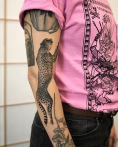 a woman wearing a pink shirt has a tattoo on her arm and the image of a cheetah