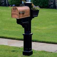 a mailbox with flowers in it sitting on the side of a sidewalk next to grass