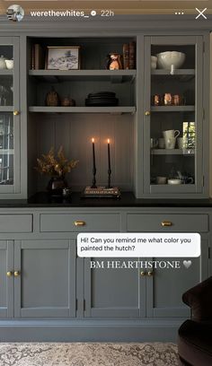 a gray china cabinet with candles and pictures on the wall above it that says, hit can you remind me what color you painted the hutch?