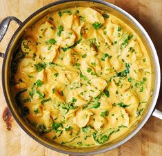 a pot filled with pasta and cheese on top of a wooden table