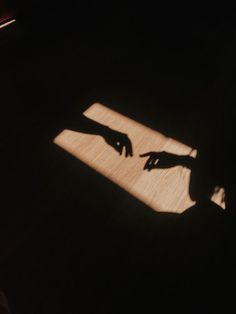 the shadow of someone's hand on a wooden floor with a light shining through it