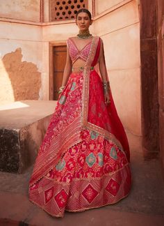 This exquisite banarsi lehenga is sumptuously paired with a coral mirrored deep V-neck blouse, inspired by the lush beauty of Mughal gardens. Intricate blooming floral motifs and delicate fauna are scattered throughout, featuring charming butterflies and birds on the lehenga panel. The sides showcase playful gota patti and motifs, adding a delightful twist to the design. The ensemble is beautifully cinched at the waist with the AG signature meenakari belt, elevating the look with a touch of elegance and sophistication. Flare Lehenga, Aditi Gupta, Chanderi Lehenga, Designer Bridal Lehenga Choli, Ogee Pattern, Embellished Belt, Model Outfit, Embroidered Dupatta, Silk Lehenga