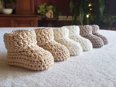 four pairs of crocheted slippers sitting on top of a bed in front of a christmas tree