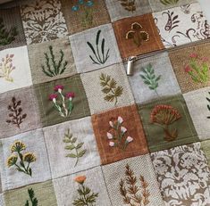 an embroidered piece of cloth with flowers and leaves on it's sides, sitting on a table