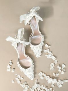 two pairs of white shoes with bows on them next to popcorn flakes in the air