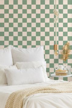 a green and white checkered wallpaper in a bedroom with a bed, night stand, lamp and side table