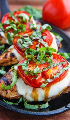 grilled chicken with tomatoes and greens on a black plate