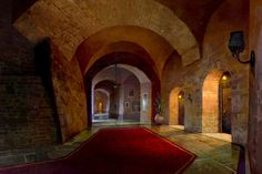 a red rug is in the middle of a hallway with arches and lights on either side