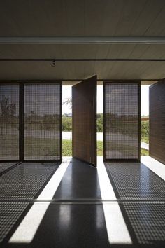 an open room with wooden slats on the walls and floor, in front of a grassy area