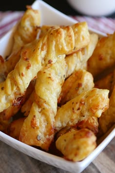 a white bowl filled with cheesy breadsticks on top of a wooden table