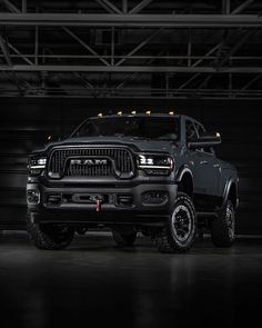 a large black truck parked in a garage next to a metal wall with lights on it