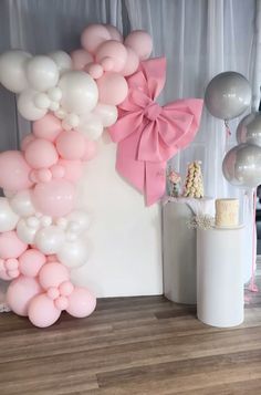 the balloon arch is decorated with pink and white balloons