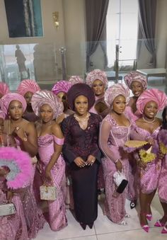 a group of women standing next to each other wearing pink dresses and head coverings