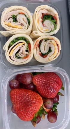 two plastic containers filled with different types of sandwiches and strawberries on top of each other