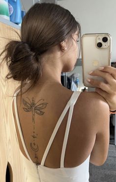 a woman with a dragon tattoo on her back taking a selfie in the mirror