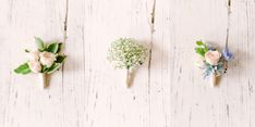 three boutonnieres with flowers on them are lined up against a white wood background