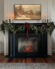 a fireplace decorated for christmas with candles and greenery on the mantel above it