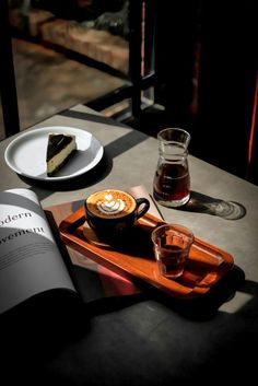 there is a piece of cake on the table next to a cup of coffee and an open book