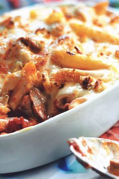 a casserole dish with meat and cheese in it on a colorful table cloth