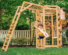 two children playing on a wooden swing set