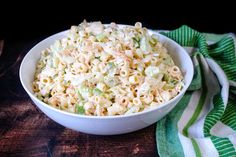 a white bowl filled with macaroni salad on top of a green and white towel