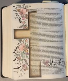 an open bible with flowers on it and the letter f painted in black ink is sitting on a table