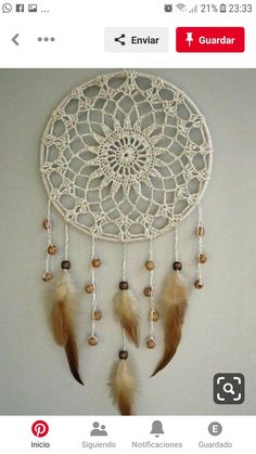 a white dream catcher with feathers hanging from it's sides on a wall next to an instagram page