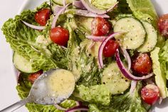 a salad with cucumbers, tomatoes and onions on it is ready to be eaten