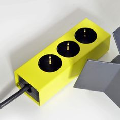 a yellow box with three black knobs and two silver square plugs on it